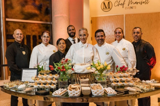 Equipo de chef Marisoll y personal de catering posando junto a mesa de aperitivos gourmet en evento elegante-catering empresarial-experiencia gastronomica.